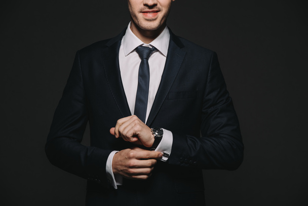 cropped view of businessman in suit touching watch isolated on black - Foto, Imagen