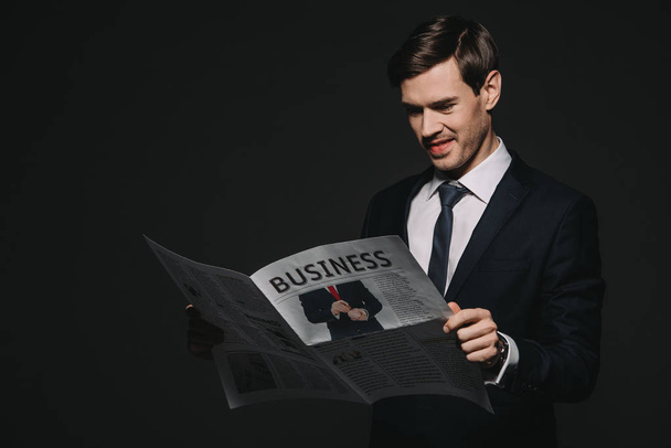 cheerful businessman reading business newspaper isolated on black - Foto, Imagen