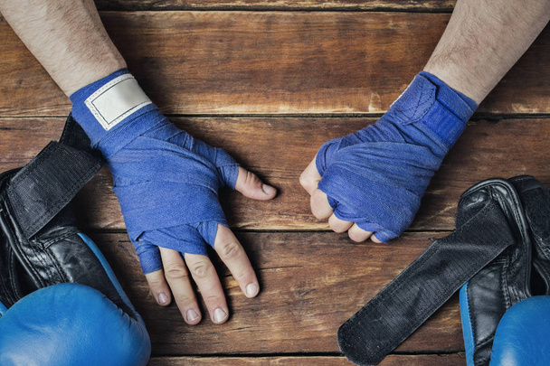 Men's hands during taping before a boxing match against a wooden background. The concept of training for boxing training or fighting. Flat lay, top view. - Photo, Image