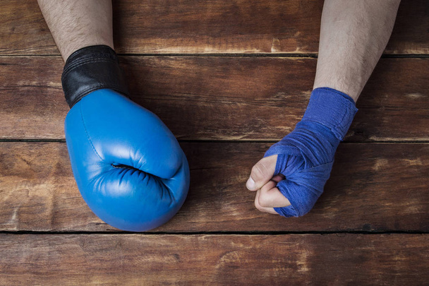 мужская рука в боксерских бинтах и боксерская перчатка на деревянном фоне. Концепция тренировок по боксу или боям. Плоский, вид сверху
. - Фото, изображение