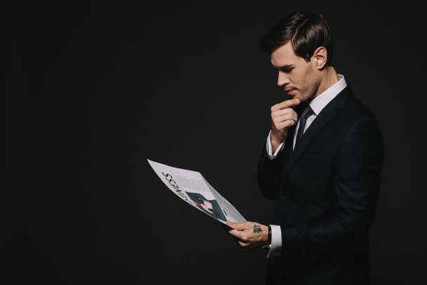 confident businessman reading business newspaper isolated on black - Zdjęcie, obraz