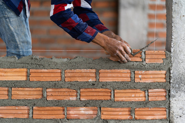 Closeup χέρι εργαζόμενος επαγγελματική κατασκευή τοποθέτηση τούβλων στην νέα βιομηχανική περιοχή. κατασκευή βιομηχανίας και τοιχοποιία έννοια - Φωτογραφία, εικόνα