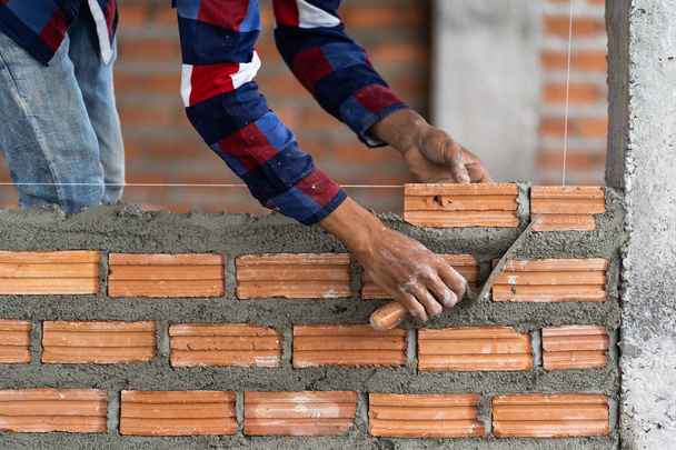 Closeup χέρι εργαζόμενος επαγγελματική κατασκευή τοποθέτηση τούβλων στην νέα βιομηχανική περιοχή. κατασκευή βιομηχανίας και τοιχοποιία έννοια - Φωτογραφία, εικόνα