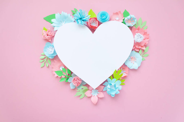 Heart frame with paper flowers with green leaves on pink background. Cut from paper. Valentines day concept - 写真・画像