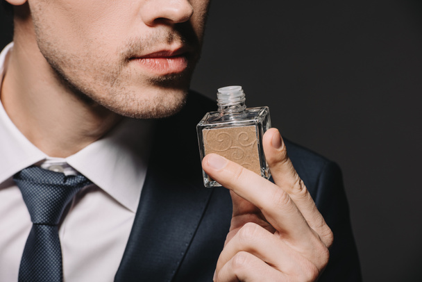 obcięty widok człowieka zapach perfum na czarnym tle - Zdjęcie, obraz