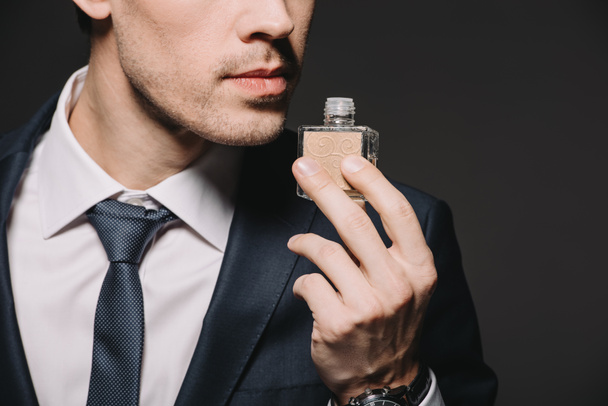 cropped view of businessman smelling perfume isolated on black - Photo, Image