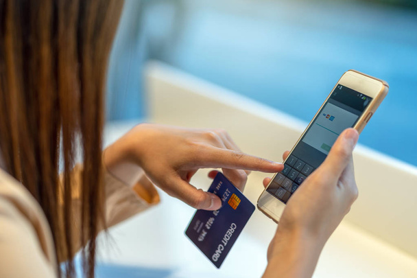 Vértes ázsiai nő használ hitelkártya mobil online vásárlás áruház ruha bolt üzlet háttér, technológia pénz pénztárca és online fizetési koncepció, hitelkártya makett felett - Fotó, kép