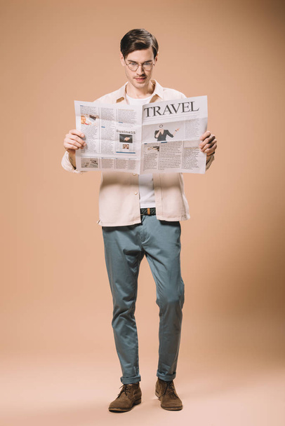 όμορφος άνδρας διαβάζει την εφημερίδα ταξίδια σε μπεζ φόντο  - Φωτογραφία, εικόνα