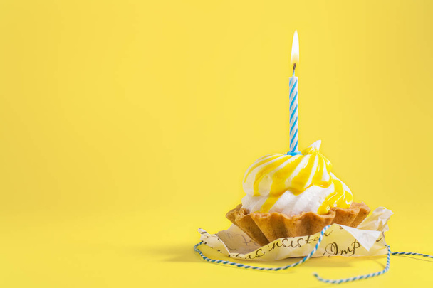 Smakelijke verjaardag cupcake met kaars op gele achtergrond met kopie ruimte. Heerlijke muffin op kleur achtergrond. Gelukkige verjaardag-concept. - Foto, afbeelding