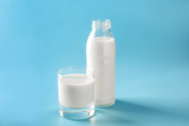 Γυαλί και μπουκάλι νόστιμο γάλα σε χρώμα φόντου - Φωτογραφία, εικόνα