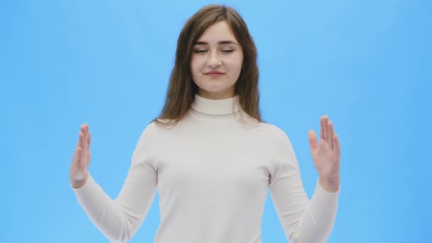 Beautiful young woman with clean, perfect skin. Portrait of beauty model with natural make-up and lift two hands up. Close-up blue background, copyspace - Filmagem, Vídeo