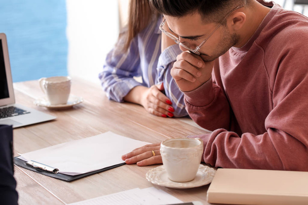 Молодая пара читает страховой договор в кафе
 - Фото, изображение