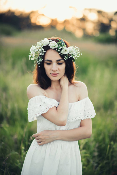 retrato de chica morena atractiva en vestido blanco y con corona floral
 - Foto, imagen