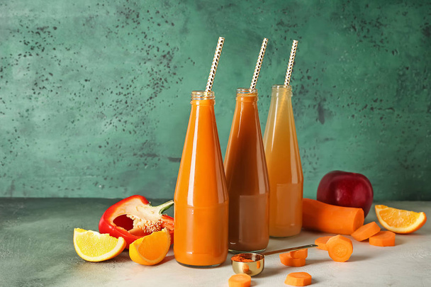 Бутылки здорового сока с ингредиентами на цветном столе
 - Фото, изображение