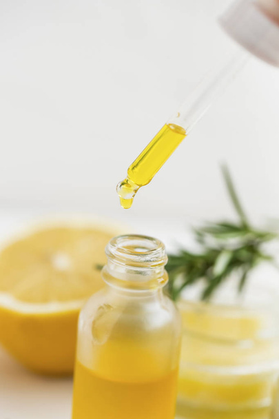 Lemon oil dropping in the bottle, aromatherapy spa herbal essential oil dropper and bottle, closeup  - Photo, Image