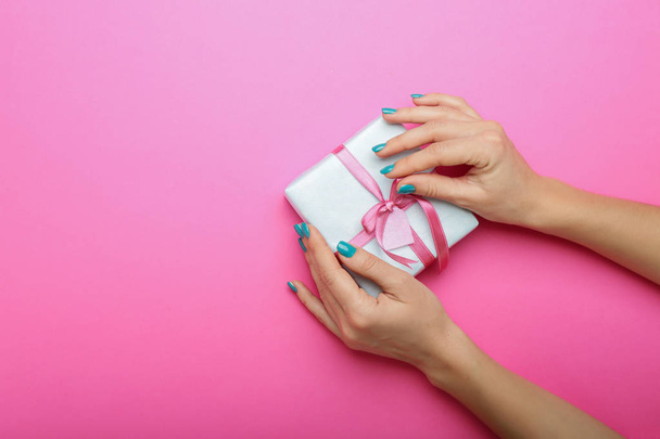 Mãos femininas com bela manicure e caixa de presente no fundo de cor
 - Foto, Imagem