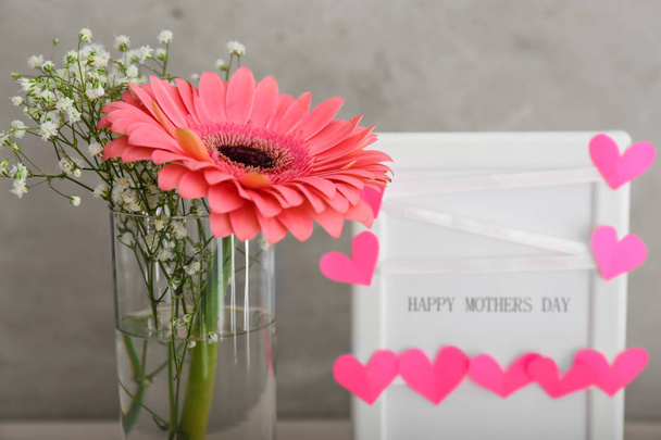 Μπουκέτο με όμορφα λουλούδια και ένα πλαίσιο με την ημέρα κείμενο ευτυχισμένη μητέρα του σε γκρίζο φόντο - Φωτογραφία, εικόνα