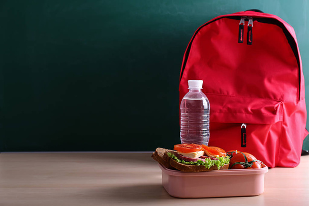 Schoolbag e lunch box con gustoso cibo in tavola
 - Foto, immagini