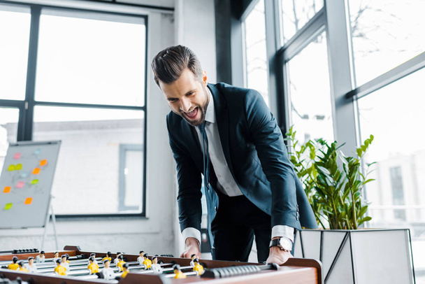 excited bearded businessman in formal wear playing table football  - Фото, изображение