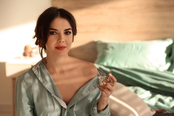 Gyönyörű fiatal nő, üveg parfüm a hálószobában - Fotó, kép