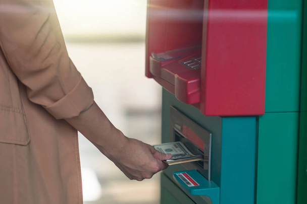 Femme de gros plan tenant le portefeuille et retirant l'argent via un distributeur automatique de billets, concept de machine de guichet automatique d'affaires
 - Photo, image