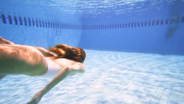 Sexy žena v bílých bikinách potápění v bazénu za slunečného dne - Záběry, video