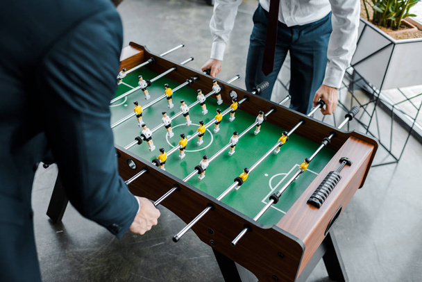 cropped view of businessmen in formal wear playing table football  - Fotografie, Obrázek