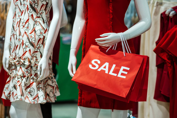 Part of female mannequin dressed in casual clothes holding the Sales paper shopping bag in the shopping department store for shopping, business fashion and advertisement concept - 写真・画像