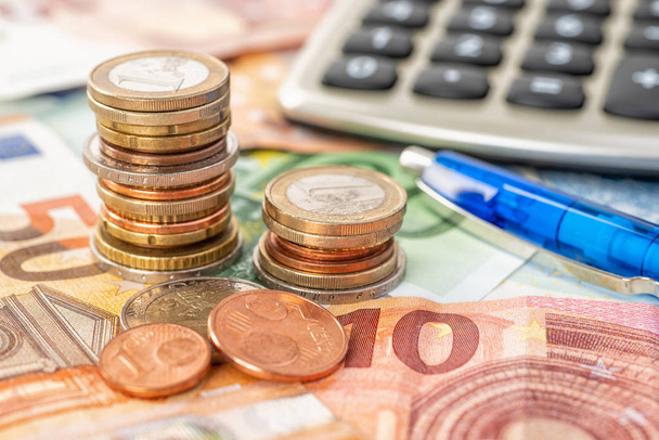 Münzhaufen auf Euro-Scheinen mit Taschenrechner - Foto, Bild
