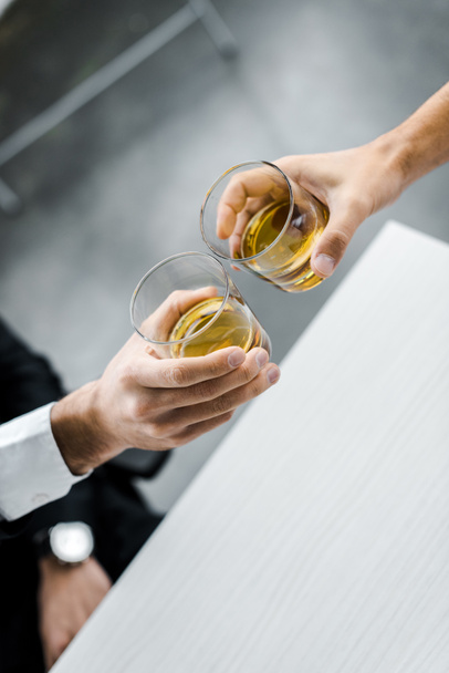 selective focus of men toasting glasses of whiskey  - Фото, изображение