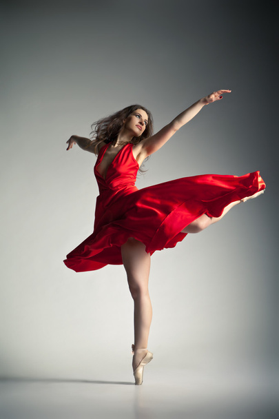 Ballet dancer wearing red dress over grey - Foto, Imagen