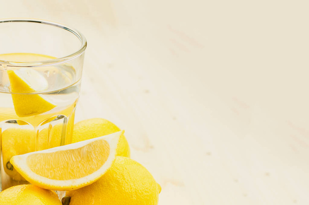 Verre d'eau avec un morceau de citron ou verre de limonade fraîche faite à la main avec des citrons sur fond en bois. Espace de copie pour le texte
. - Photo, image