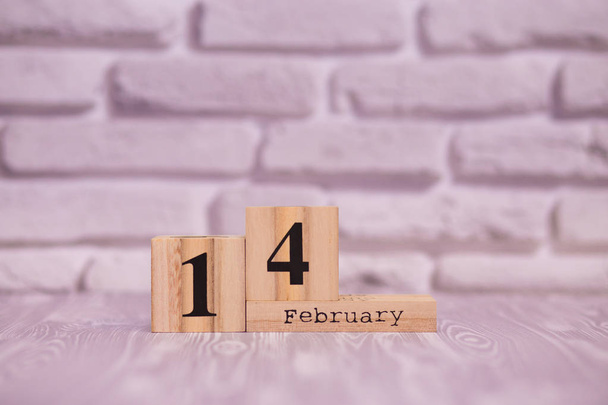 14 februari ingesteld op houten kalender met witte bakstenen achtergrond. - Foto, afbeelding