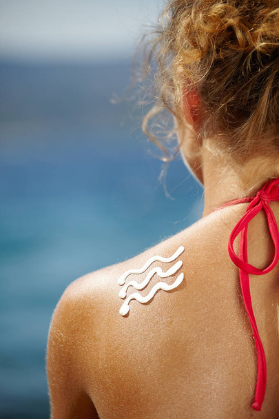 Donna con crema abbronzante in spiaggia sotto forma di onde
 - Foto, immagini