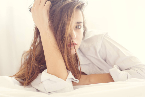 Seksikäs nuori nainen poseeraa sängyllä
 - Valokuva, kuva