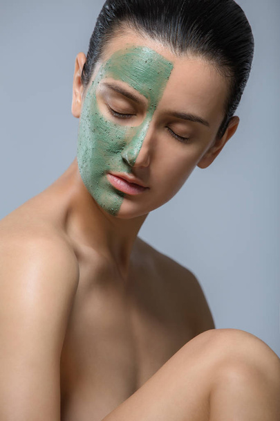 Jonge vrouw met groene gezichtsmasker - studio portret - Foto, afbeelding