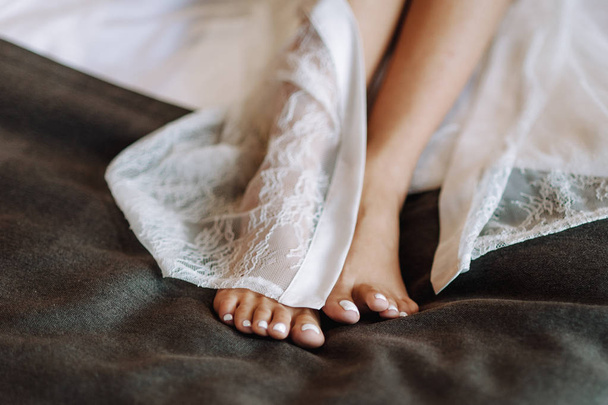 beautiful bare legs of the bride under veil lying on the bed - Fotografie, Obrázek