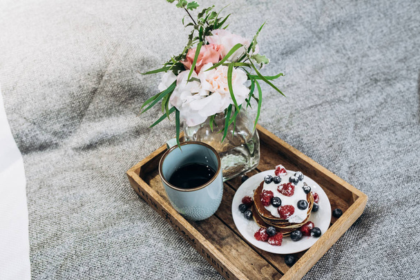 Coffee, flowers and pancakes with berries on the bed. breakfast in bed to the bride. soft focus - Photo, Image