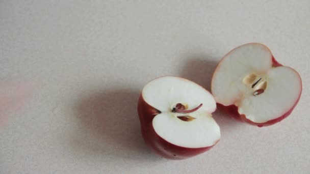männliche Hand getrennt schneiden roten Apfel in zwei Teile auf dem Tisch. Männerhand hält einen roten Apfel mit Wassertropfen. Veganer bereiten Obst zum Mittagessen zu. Blick von oben. flache Lage - Filmmaterial, Video
