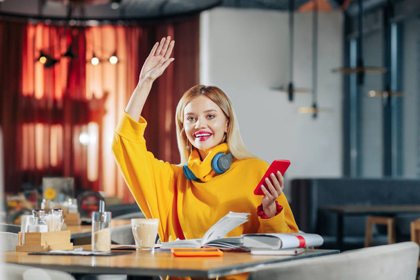 Blonde-haired woman raising her hand while calling for waiter - Foto, Imagem