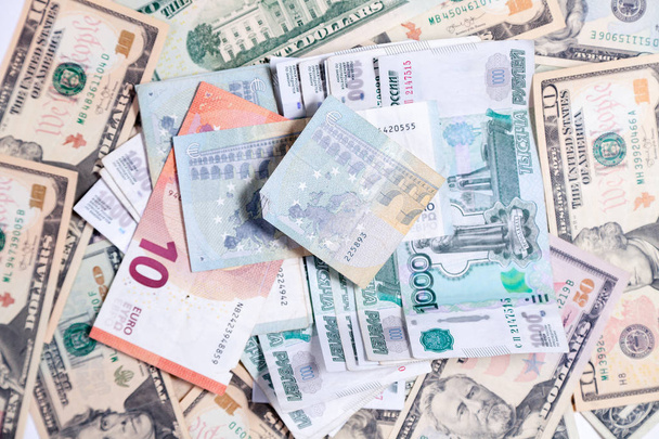 Closeup many american dollar, euro and rubles banknotes, cash. Concept leap, fall, rate, currency exchange, debt, profit, loss, sanctions, appreciation of goods, inflation - Photo, image