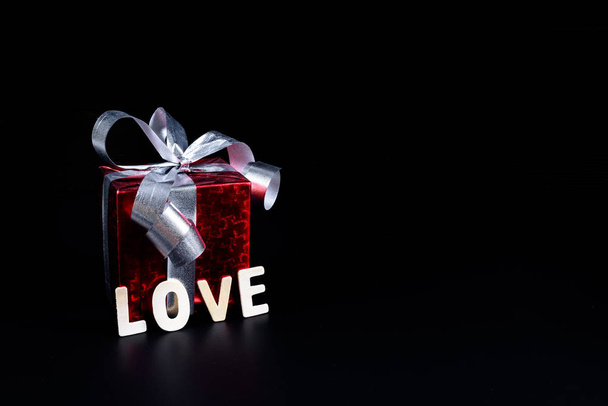 Valentine's day Concept Gift box and Wooden letters word "LOVE" on black background and empty space for your graphic. Reminder for couples to express love - Zdjęcie, obraz