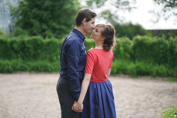 agradable pareja adulta amable caminando en el verde jardín de verano, abrazo, sonrisa y beso en el amor
 - Foto, imagen