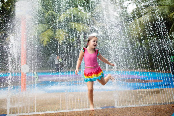 Kids play in aqua park. Children at water playground of tropical amusement park. Little girl at swimming pool. Child playing at water slide on summer vacation in Asia. Swim wear for young kid. - Photo, Image