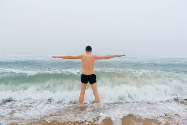 man standing in cold stormy sea - Foto, afbeelding