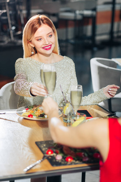 Woman wearing bright beige dress holding glass of champagne - Foto, afbeelding