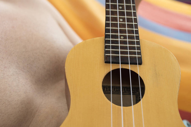 Detalhe do homem relaxando em uma rede e jogando ukulele
. - Foto, Imagem