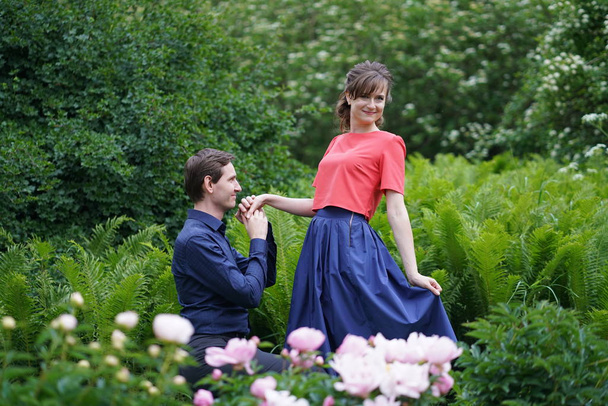 hombre de rodillas hace una oferta para ser su esposa a una mujer en un jardín floreciente de verano
 - Foto, Imagen