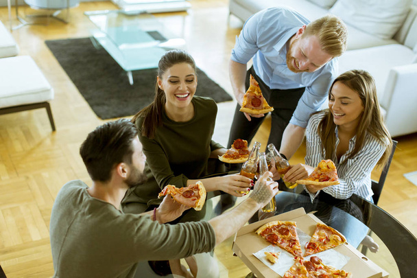 Groupe de jeunes gens heureux mangeant de la pizza et buvant du cidre dans l'intérieur moderne
 - Photo, image