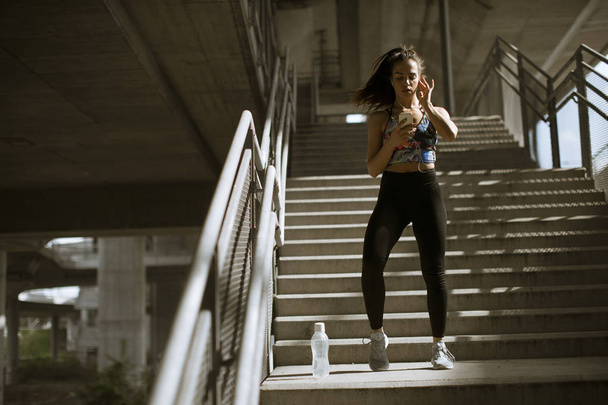 Молодая фитнес-женщина делает упражнения на открытом воздухе в городской среде
 - Фото, изображение